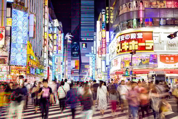 Crowd of People Crossing big zebra crossing at night, lit by neon signs in Tokyo, Japan